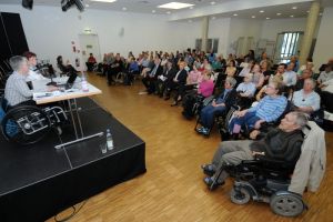 Auf der Bühne die Referentin Dr. Sigrid Arnade und Elke Campioni im Plenum Besucher und Besucherinnen 